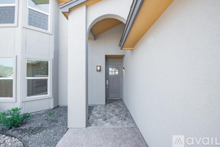 A modern house entrance with a grey door and a grey gravel path.