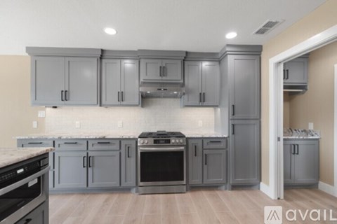 A kitchen with grey cabinets and appliances.