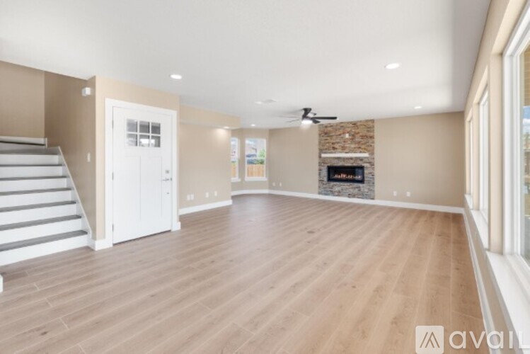 A spacious living room with wooden flooring and a fireplace.