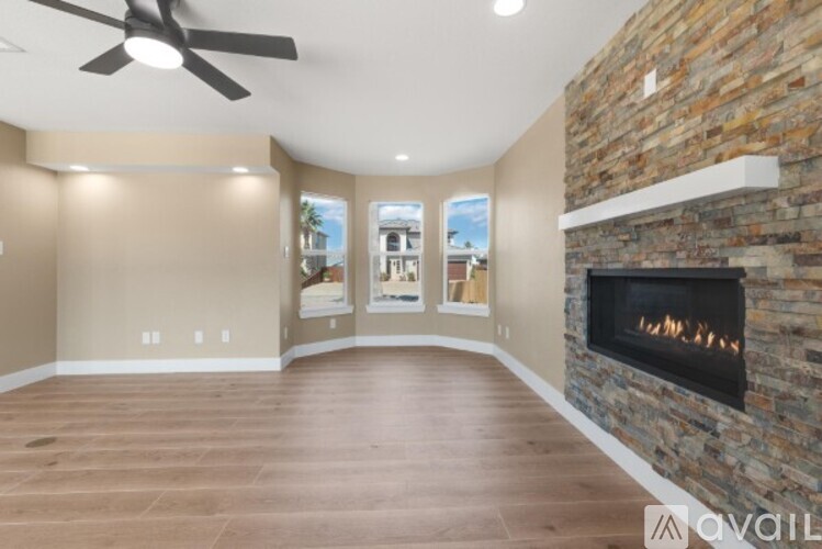 A living room with a stone fireplace and a ceiling fan.