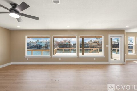A room with a ceiling fan and three windows overlooking a pool.