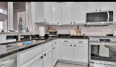 A kitchen with white cabinets and a black countertop.