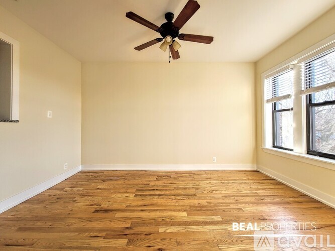 A room with a ceiling fan and wooden flooring.