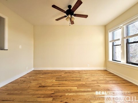 A room with a ceiling fan and wooden flooring.