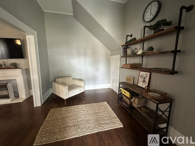 A living room with a white chair and a brown rug.