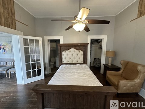 A bedroom with a large bed and a ceiling fan.