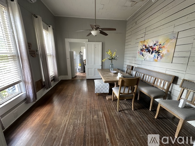 A dining room with a wooden floor and a ceiling fan.