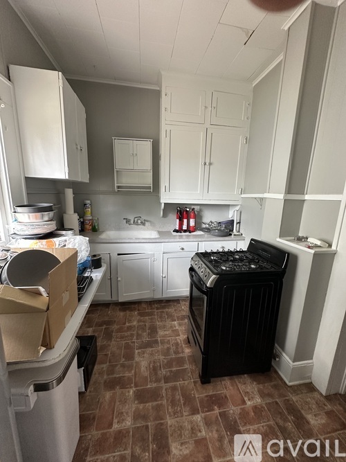 A kitchen with a black dishwasher and white cabinets.