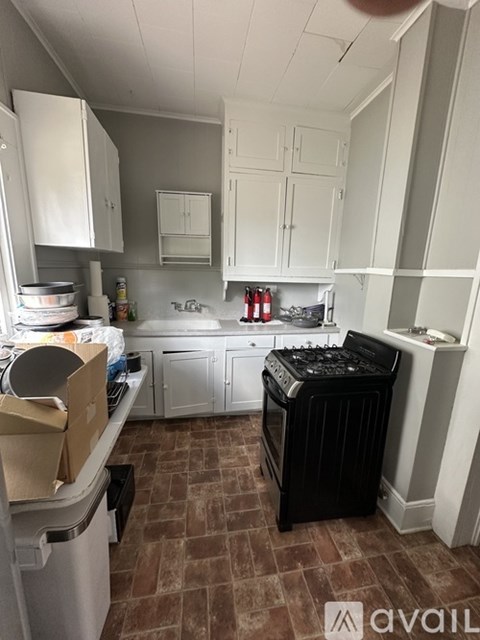 A kitchen with a black dishwasher and white cabinets.