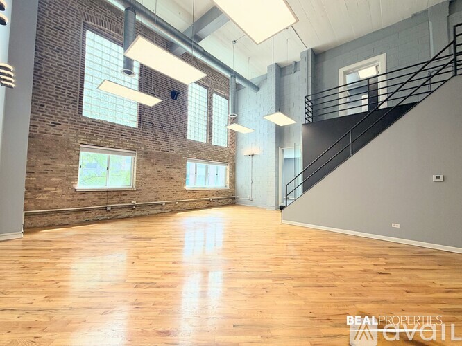 A spacious room with wooden floors and a staircase.