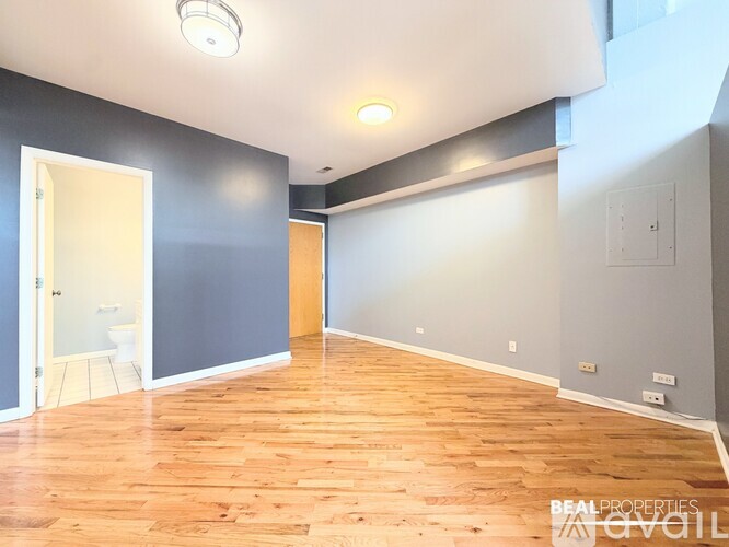 A spacious room with wooden flooring and white walls.