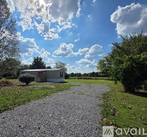 A gravel path leads to a house in a rural setting.
