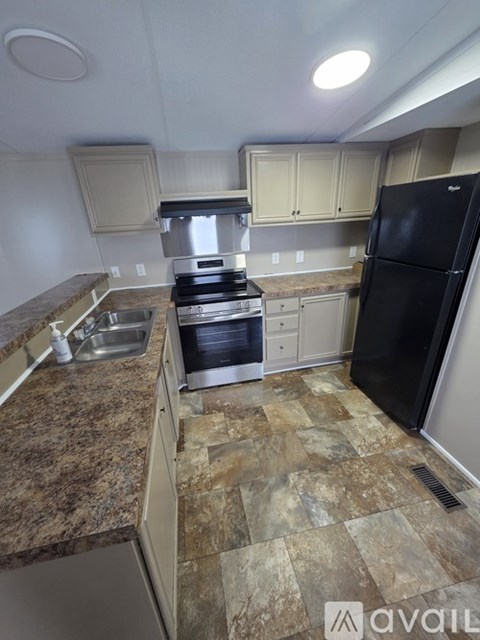 A kitchen with granite countertops and a black refrigerator.