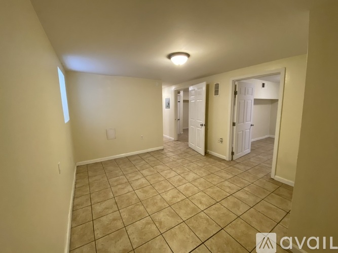 A spacious room with tiled flooring and a single light fixture on the ceiling.
