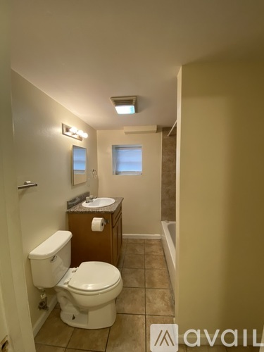 A bathroom with a toilet, sink, and mirror.