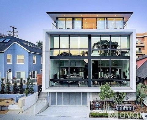 A modern house with a large glass front and a small garden in front.