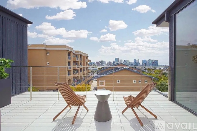 Two chairs and a table are on a patio overlooking a city skyline.