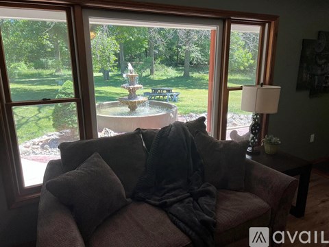 A living room with a couch and a view of a garden through the window.