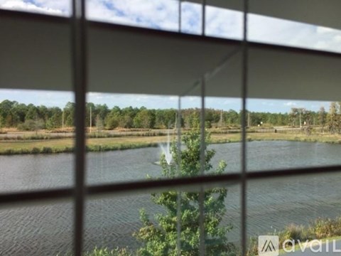 A view of a body of water through a window with trees in the distance.