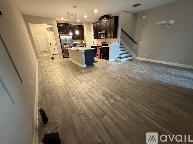 A spacious room with wooden flooring and a staircase leading to the upper level.