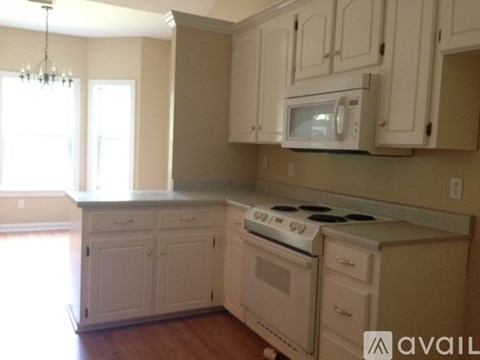 A kitchen with white cabinets and a stove top oven.