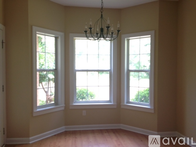 A room with a chandelier and three windows.