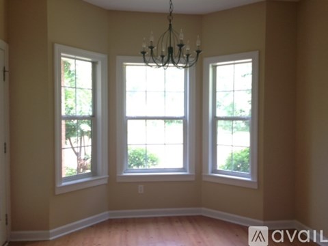 A room with a chandelier and three windows.