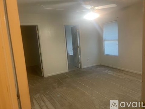 A room with a ceiling fan and light, and a door leading to another room.