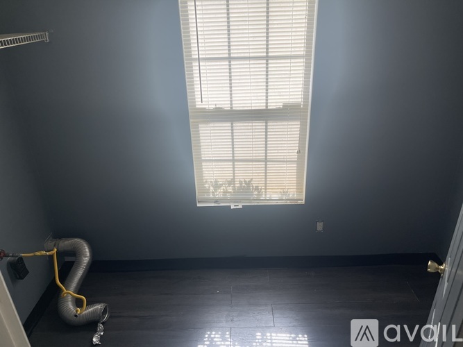 A room with a window and a yellow hose on the floor.