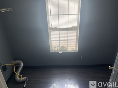 A room with a window and a yellow hose on the floor.