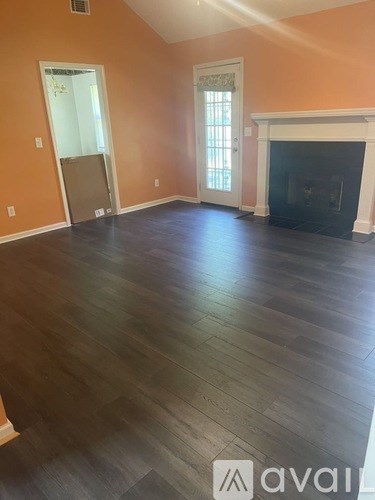 A room with a fireplace and wood flooring.