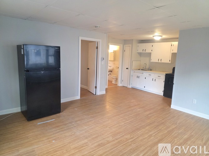 A kitchen with white cabinets and a black fridge is available for rent.