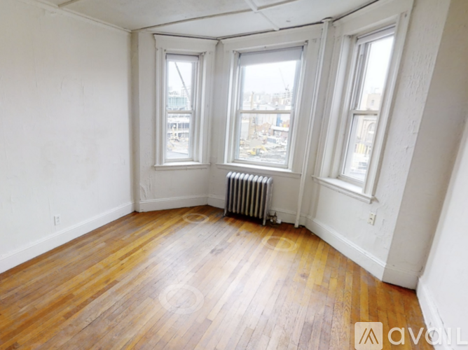 A room with wooden floors and three windows.