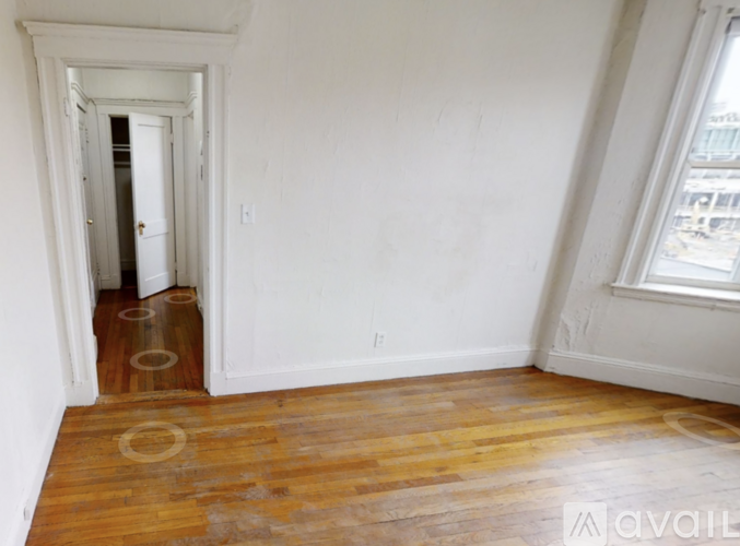 A room with wooden floors and a doorway leading to another room.