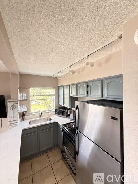 A kitchen with a stainless steel refrigerator and a sink with a faucet.