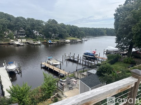 A dock with boats and a house in the background.