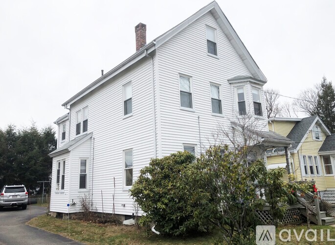 A white house with a grey roof and a chimney.