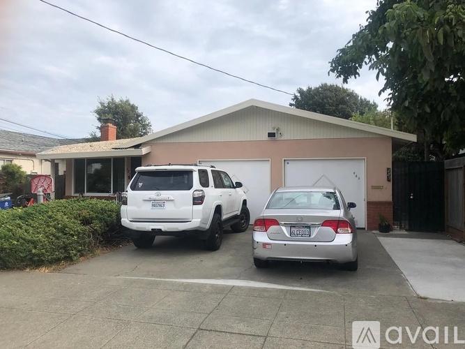 Two cars are parked in front of a house.