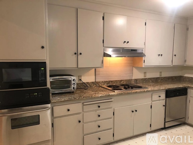 A kitchen with white cabinets and a granite countertop.