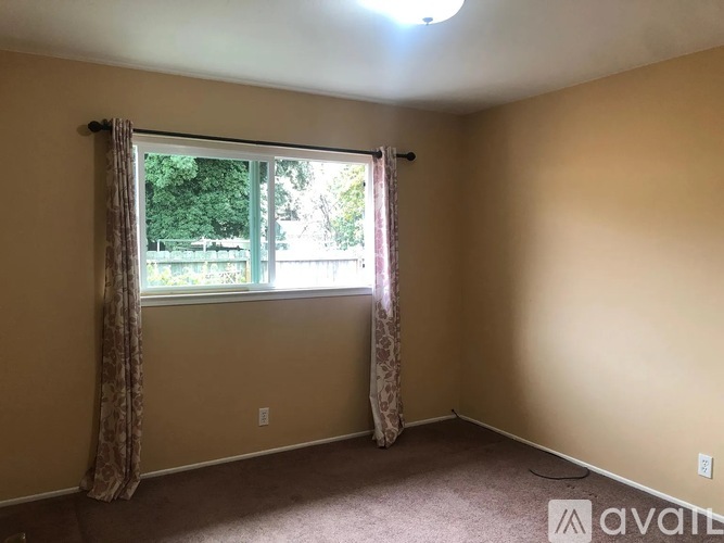 A room with a window and curtains is available for rent.