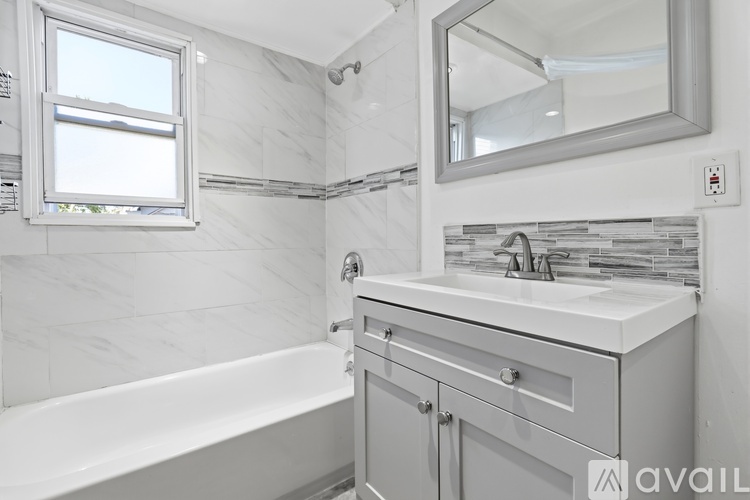 A bathroom with a white tub, sink, and mirror.