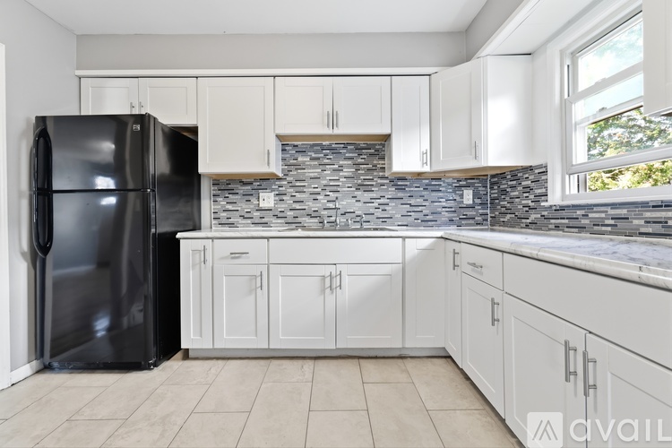 A kitchen with a black refrigerator and white cabinets.