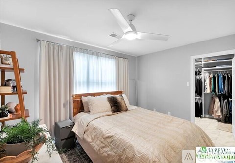 A bedroom with a large bed and a ceiling fan.