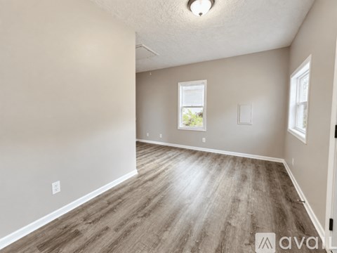 A spacious room with wooden flooring and a window.