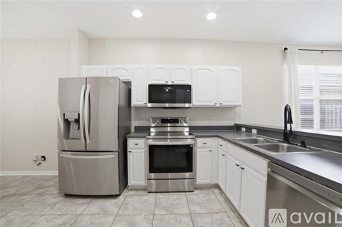 A kitchen with a stainless steel refrigerator and oven, and white cabinets.