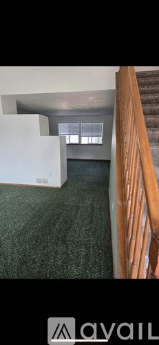 A room with a carpeted floor and a staircase.