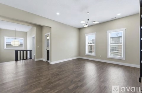 A spacious room with wooden floors and a ceiling fan.