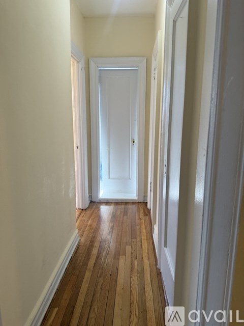 A long hallway with a white door at the end.