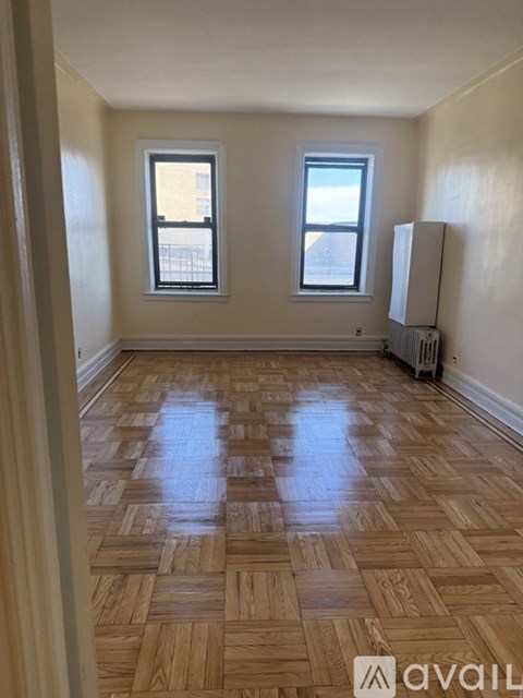 A room with wooden flooring and two windows.
