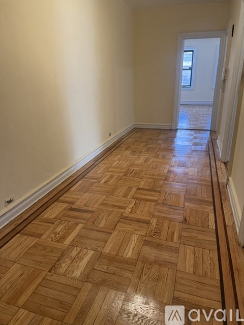 A room with wooden flooring and a doorway leading to another room.